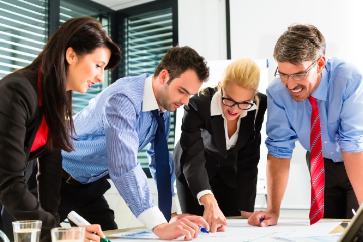 group of employees circled around documents reviewing information