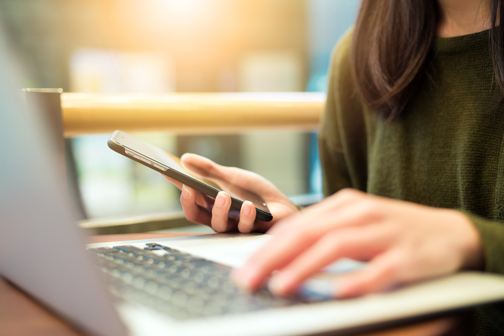 woman-connecting-cellphone-and-laptop-computer